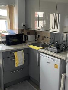 a kitchen with a sink and a microwave at Homestay 1bedroom in family home with small wet room and own entrance in Great Barr