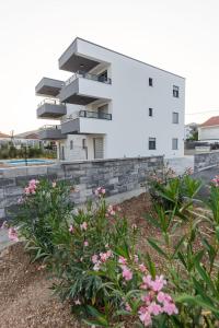 Apartments Antico في تروغير: مبنى أبيض بالورود الزهرية أمامه