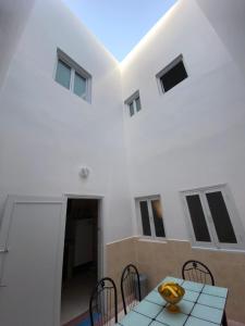 Cette chambre blanche dispose d'une table, de chaises et de fenêtres. dans l'établissement Panorama guest house, à Sidi Ifni