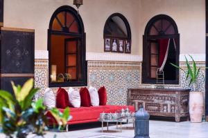 uma sala de estar com um sofá vermelho e duas janelas em Riad Yacout em Meknès