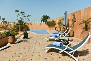 un patio con sillas, una sombrilla y una piscina en Riad Yacout, en Meknès