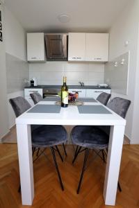 Apartman Cinkopan Premantura 1 في بريمونتيرا: طاولة غرفة طعام بيضاء مع زجاجة من النبيذ