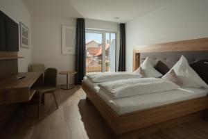 een slaapkamer met een bed, een bureau en een raam bij Gasthof Hosbein in Heiligenberg