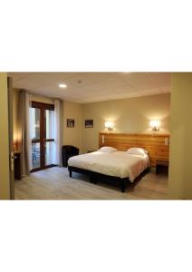 a bedroom with a large bed with a wooden headboard at Hôtel Belleville in Lamalou-les-Bains