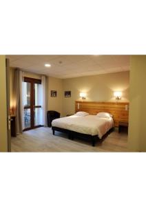 una camera da letto con un letto grande con testiera in legno di Hôtel Belleville a Lamalou-les-Bains