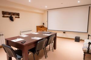 una sala conferenze con tavolo, sedie e schermo proiettore di HOTEL POSADA LaS RETAJAS a Medinaceli