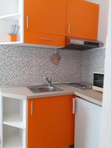 a kitchen with orange cabinets and a sink at Apartmani Vlaho in Molunat