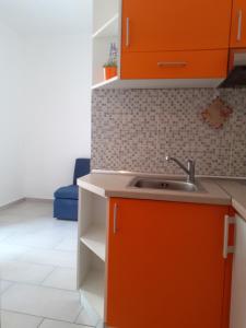 - une cuisine avec des armoires orange et un évier dans l'établissement Apartmani Vlaho, à Molunat