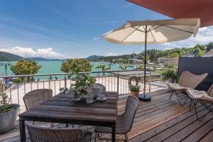 a wooden deck with a table and chairs and an umbrella at Seeapartment da Leopoldo I in Velden am Wörthersee