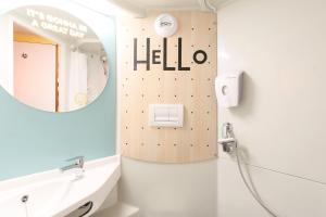 La salle de bains est pourvue d'un lavabo et d'un miroir avec des mots bonjour. dans l'établissement Premiere Classe Marseille Vitrolles Aéroport, à Vitrolles