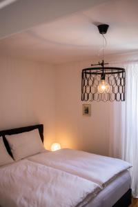 a bedroom with a white bed and a chandelier at Seeapartment da Leopoldo I in Velden am Wörthersee