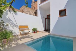 a house with a swimming pool next to a white wall at Es Colomer 265 by Mallorca Charme in Muro