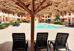 two chairs under an umbrella next to a swimming pool at Sunshine home Sal in Santa Maria