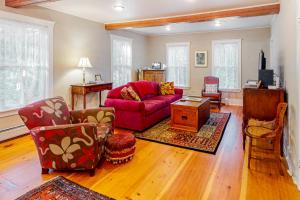 a living room with a red couch and chairs at Farmhouse on the Cove in Penobscot