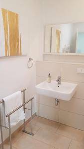 een badkamer met een wastafel, een spiegel en een stoel bij Penthouse Nähe Frankfurt am Main in Hanau am Main
