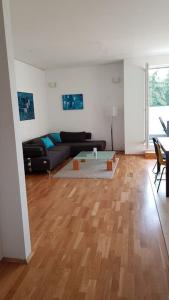 een woonkamer met een zwarte bank en een houten vloer bij Penthouse Nähe Frankfurt am Main in Hanau am Main