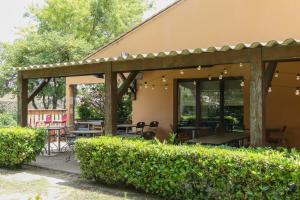 an outdoor patio with a pergola and tables and chairs at HÔTEL KYRIAD MARSEILLE - Vitrolles Aéroport in Vitrolles