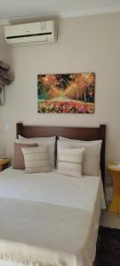 um quarto com uma cama branca e uma pintura na parede em Hospedagem Quarto Chic centro Cunha em Cunha