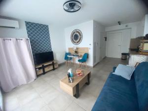 ein Wohnzimmer mit einem blauen Sofa und einem TV in der Unterkunft Chez Candie in La Trinité