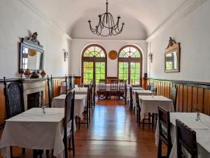 uma sala de jantar com mesas e cadeiras e um lustre em Hotel Solar de Monfalim em Évora