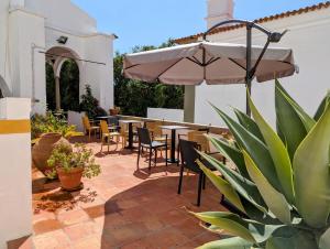 d'une terrasse avec des tables, des chaises et un parasol. dans l'établissement Hotel Solar de Monfalim, à Évora