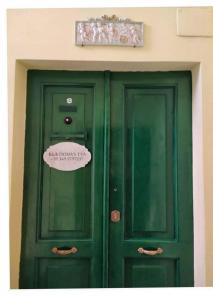 twee groene deuren in een gebouw met een bord erop bij B&B Domvs tva in Chieti