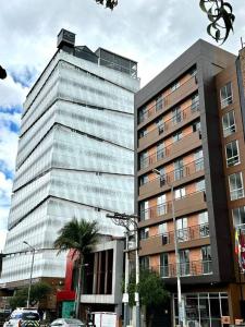 a tall building with a palm tree in front of it at Exclusivos Aptos amoblados en el edificio Cabrera 85-12 in Bogotá