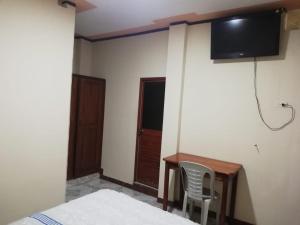 a bedroom with a desk and a tv on the wall at Hostal Amazónico Bello Amanecer in Nueva Loja