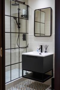 a bathroom with a sink and a shower with a mirror at Livestay-Stunning Apartment With Private Balcony & River Views in London