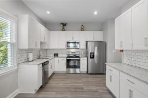a kitchen with white cabinets and a stainless steel refrigerator at Beautiful Condo Near Boardwalk Beach & Downtown in Ocean City