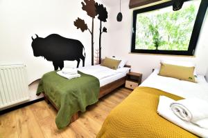 a bedroom with two beds and a bear on the wall at Za Górami in Wetlina