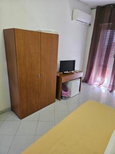 Zimmer mit einem Holzschrank und einem Schreibtisch mit einem Computer in der Unterkunft Hotel Souvenir in Ercolano