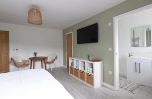 een witte slaapkamer met een bed en een tafel bij The Garden Room in Delabole