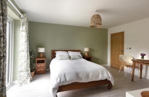una camera da letto con letto, lenzuola e cuscini bianchi di The Garden Room a Delabole