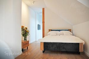 sypialnia z łóżkiem i wazonem kwiatów w obiekcie Mazury Haus w mieście Ruciane-Nida