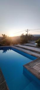 una piscina azul con puesta de sol en el fondo en Mira Pombeira, en Castro Daire