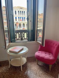 a pink chair and a table in a room with a window at Royal Rialto Apartment - Grand Canal View in Venice