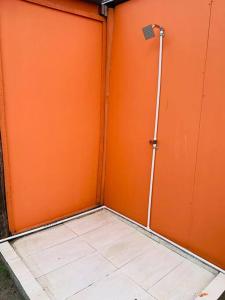 a room with an orange wall with a shower at Mini Casa Campestre Privada in La Playa