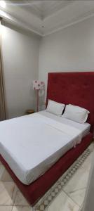 1 dormitorio con 1 cama blanca grande y cabecero rojo en Marrakech Palmeraie village, en Marrakech