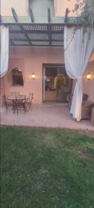 馬拉喀什的住宿－Marrakech Palmeraie village，庭院配有桌椅和白色窗帘