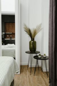 M & N Guesthouse في فولوس: غرفة نوم بسرير و مزهرية على طاولتين