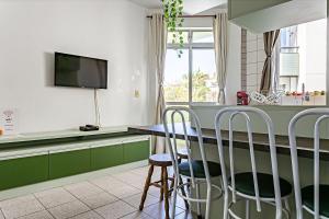 a kitchen with green cabinets and a table with stools at Apto a 30 metros do mar em Canasvieiras CBE105 in Florianópolis