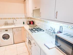 a kitchen with a stove top oven next to a washing machine at Wimbledon Apartment in London