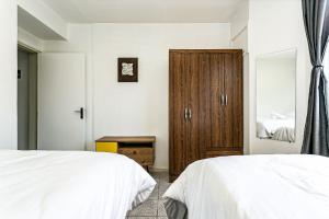 a bedroom with two beds and a wooden cabinet at Apto a 30 metros do mar em Canasvieiras CBE105 in Florianópolis