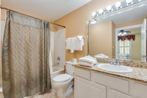 a bathroom with a toilet and a sink and a mirror at Calypso Resort - Direct gulf front Condo with king master, and Free Wi-Fi in Panama City Beach +40 photos