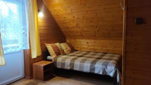 a small room with a bed in a wooden cabin at Domki Żaklin in Polańczyk