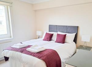 a white bedroom with a large bed with towels on it at Wimbledon Apartment in London