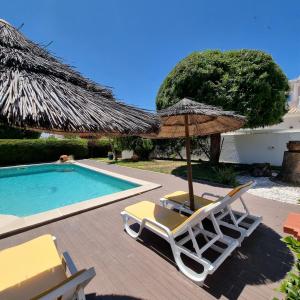 a pair of chairs and an umbrella next to a swimming pool at Casa Dos Cedros in Lagos