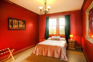 um quarto com paredes vermelhas, uma cama e uma janela em The Ghost Lodge em Granity