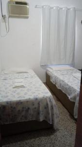 two beds in a small room with a window at Hotel Porto da Lua Belém in Belém